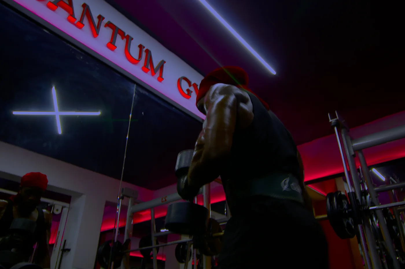 Athlete performing a heavy dumbbell press under the Quantum Gym sign