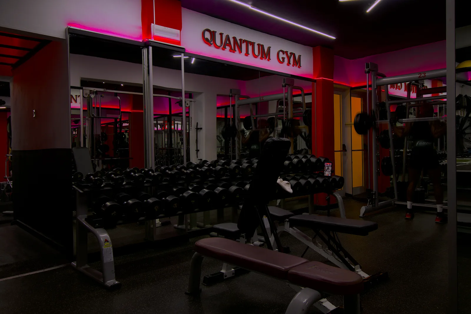Quantum Gym floor — dumbbell racks under the Quantum Gym sign